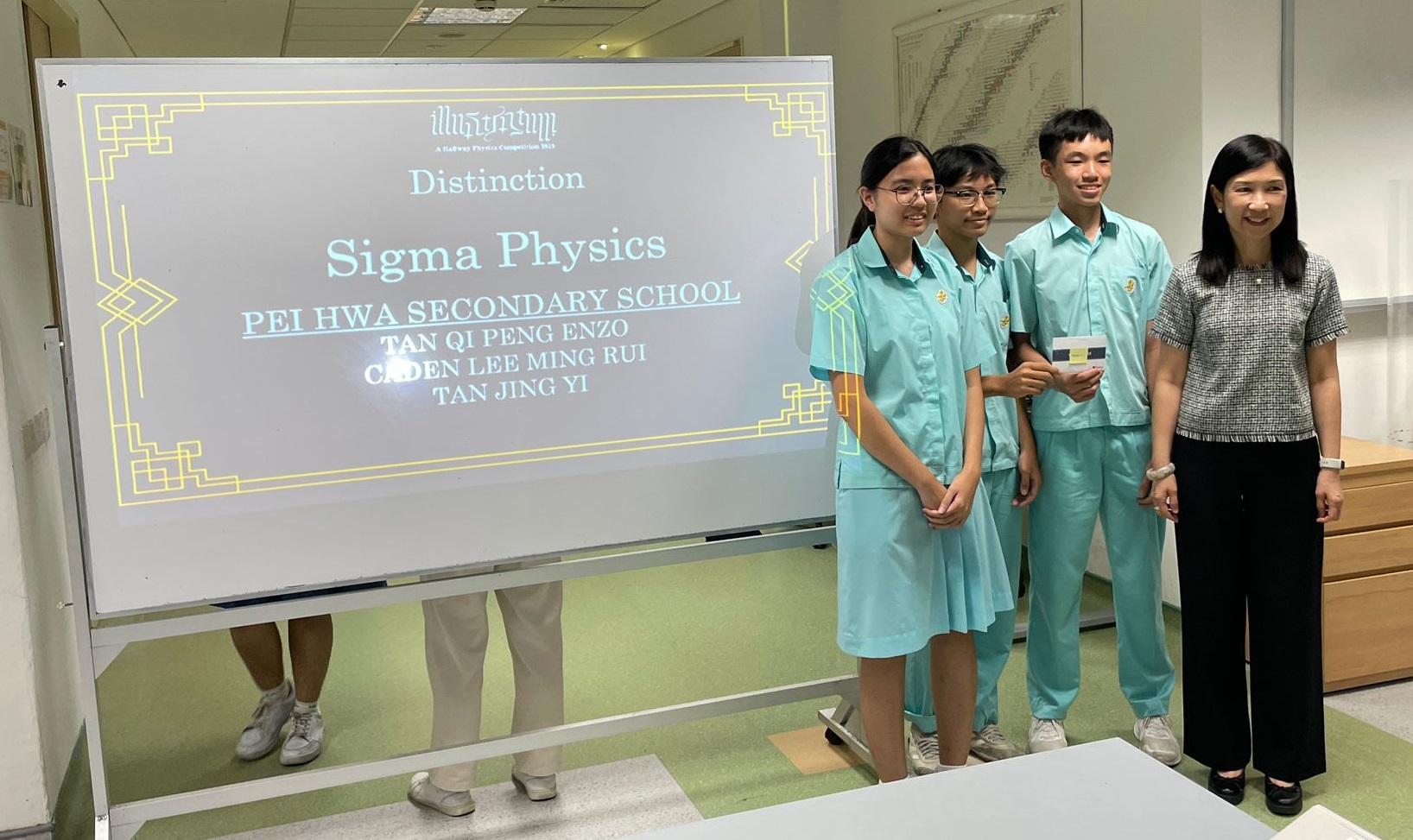 3 students holding their award taking photo with the organizer